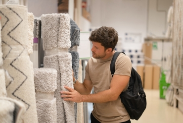 Man choosing rugs from rack