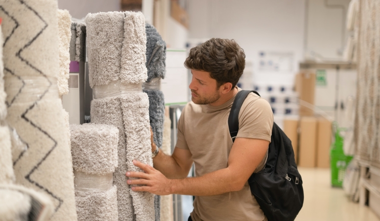 Man choosing rugs from rack